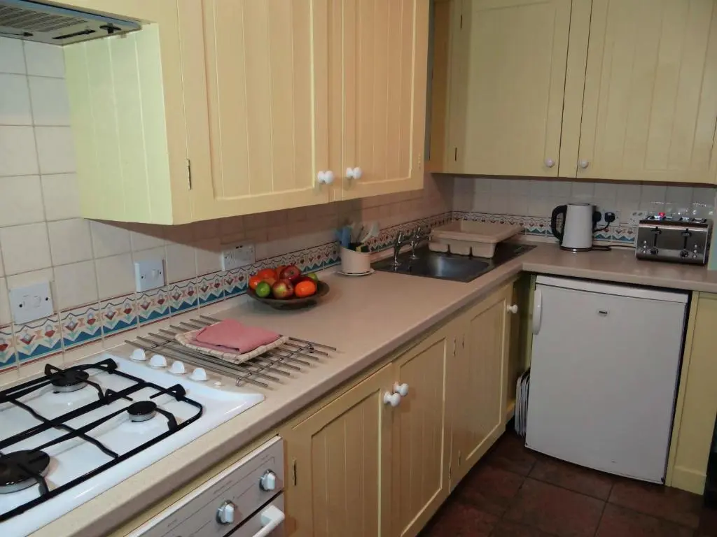 a kitchen with a stove and a bowl of fruit on the counter at The Cottage Bogroy in Carrbridge
