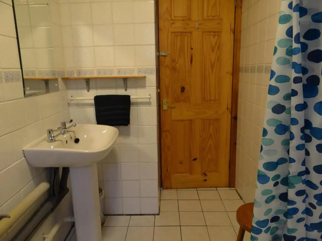 a bathroom with a sink and a wooden door at The Cottage Bogroy in Carrbridge