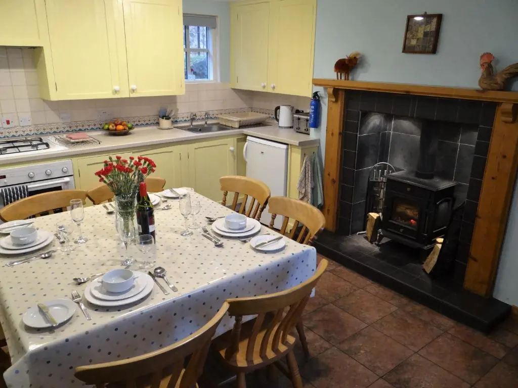a kitchen with a table with chairs and a fireplace at The Cottage Bogroy in Carrbridge