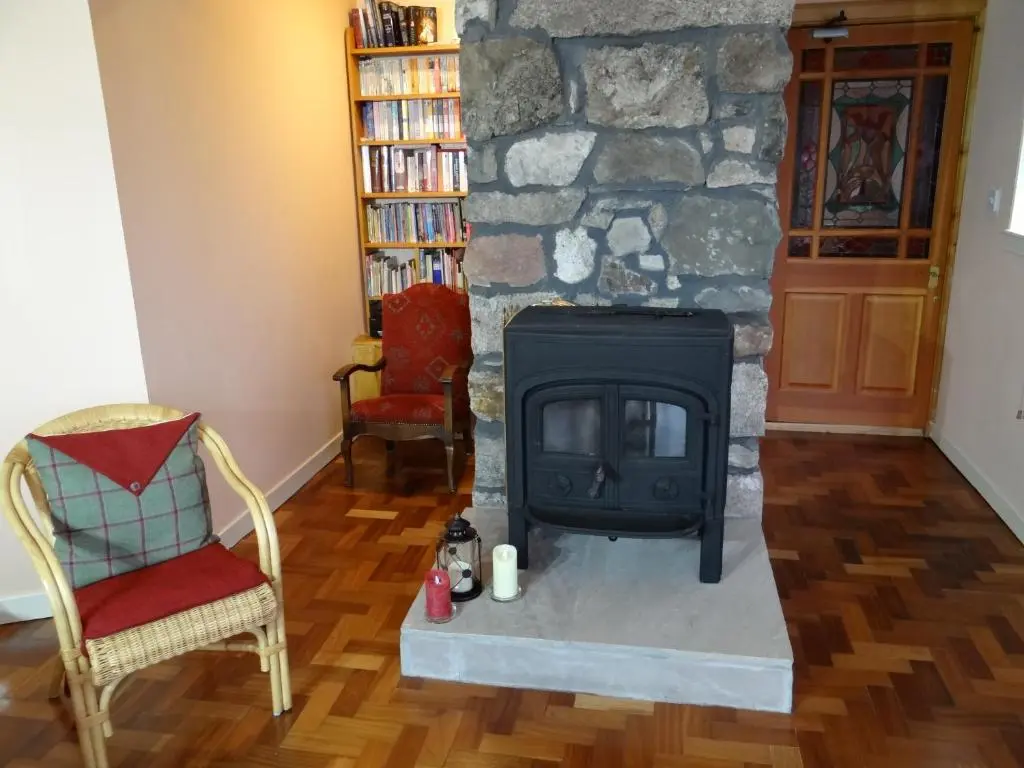 a fireplace in a living room with a stone wall at The Cottage Bogroy in Carrbridge