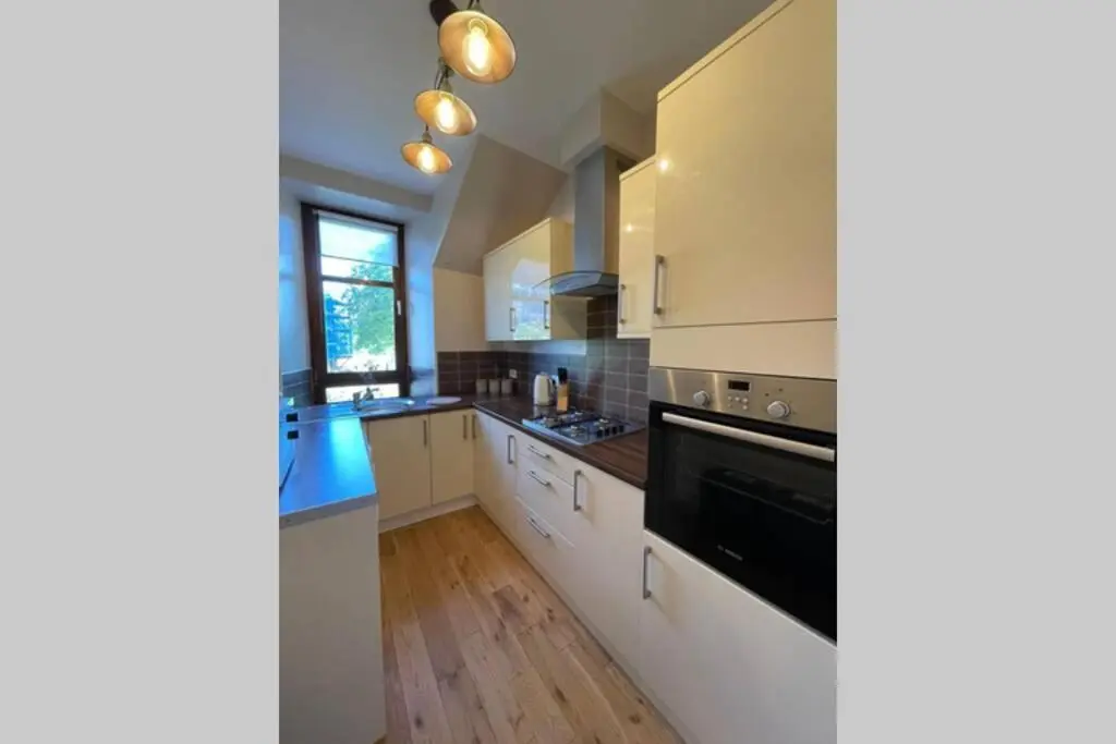 a kitchen with white cabinets and a black oven at No 10 Immaculate City Centre, Top Floor 2 Bed Flat with Free Parking in Inverness