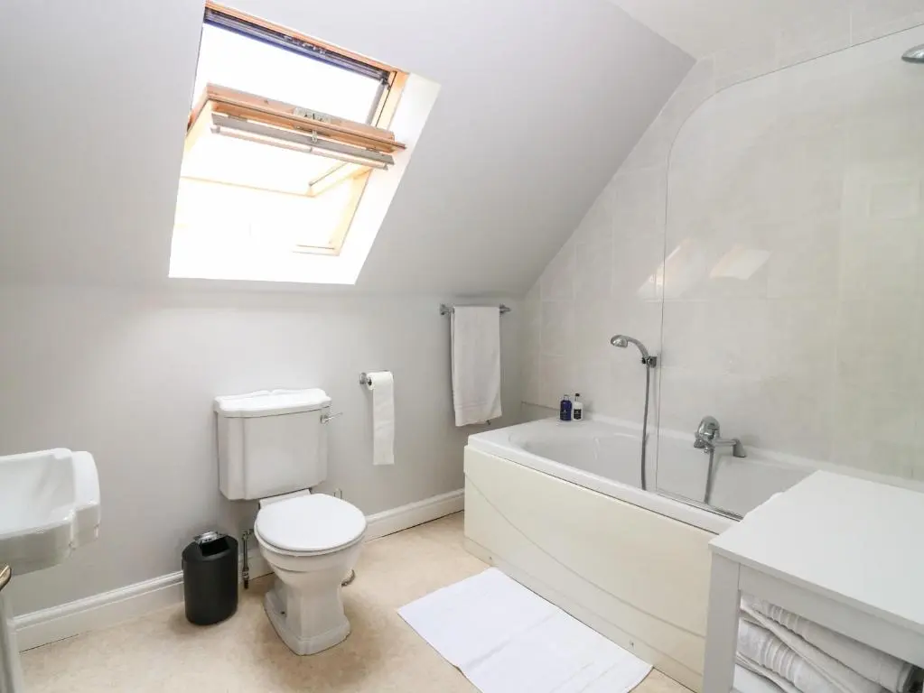 a white bathroom with a toilet and a bath tub at Tombeck in Tomintoul