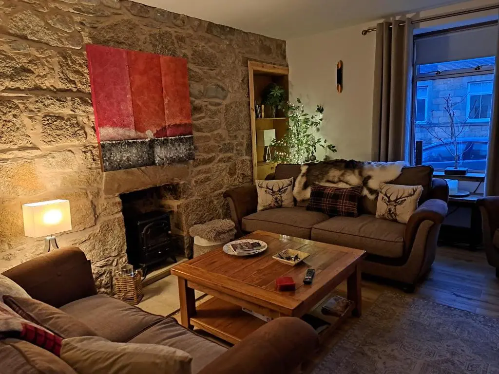 a living room with couches and a stone wall at The Apartment in Aberlour in Aberlour