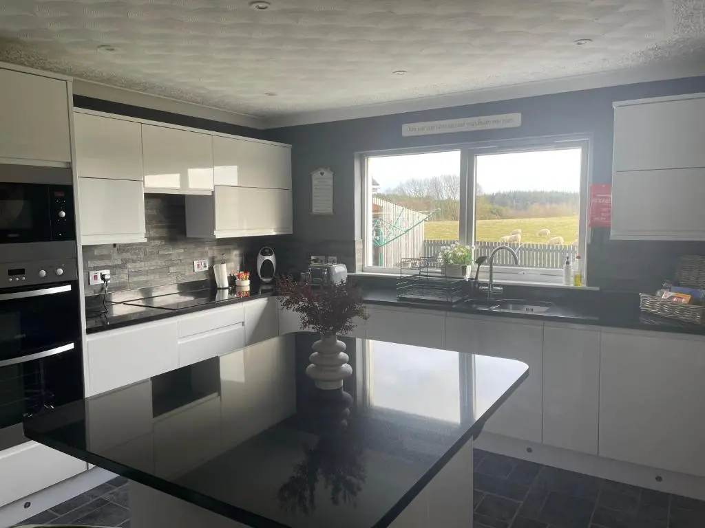 a kitchen with white cabinets and a glass counter top at Gleneden House in Tore