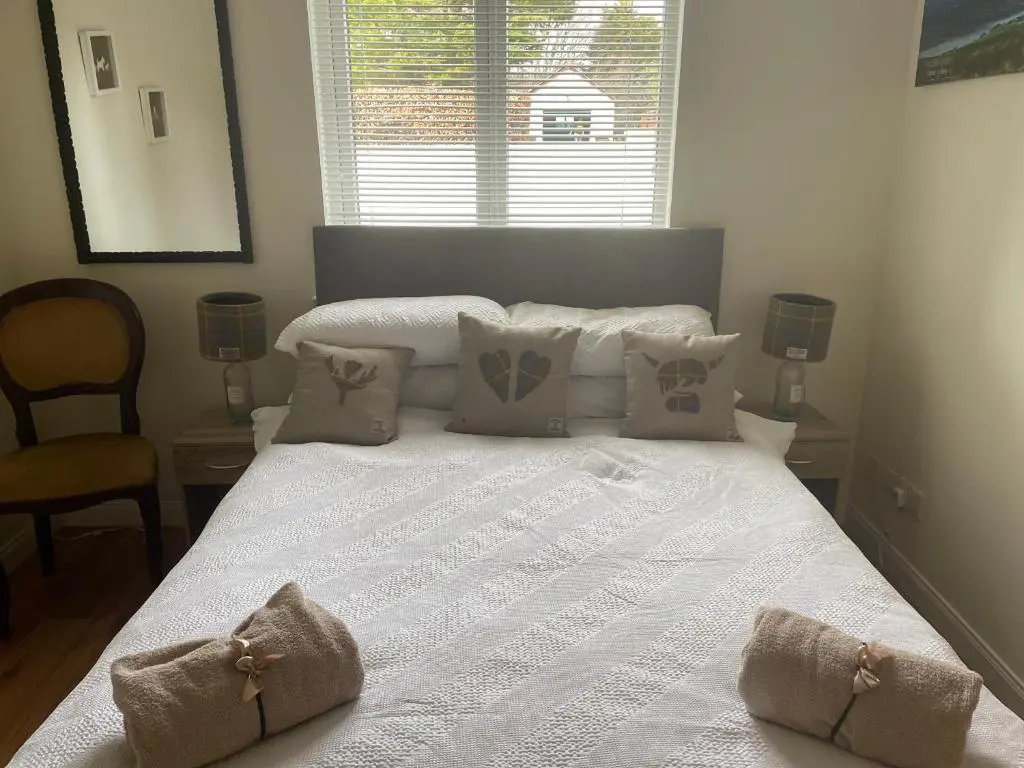 a large white bed in a bedroom with a window at Gleneden House in Tore