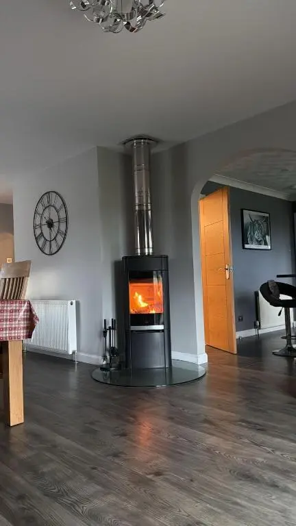a living room with a fireplace in the middle of a room at Gleneden House in Tore