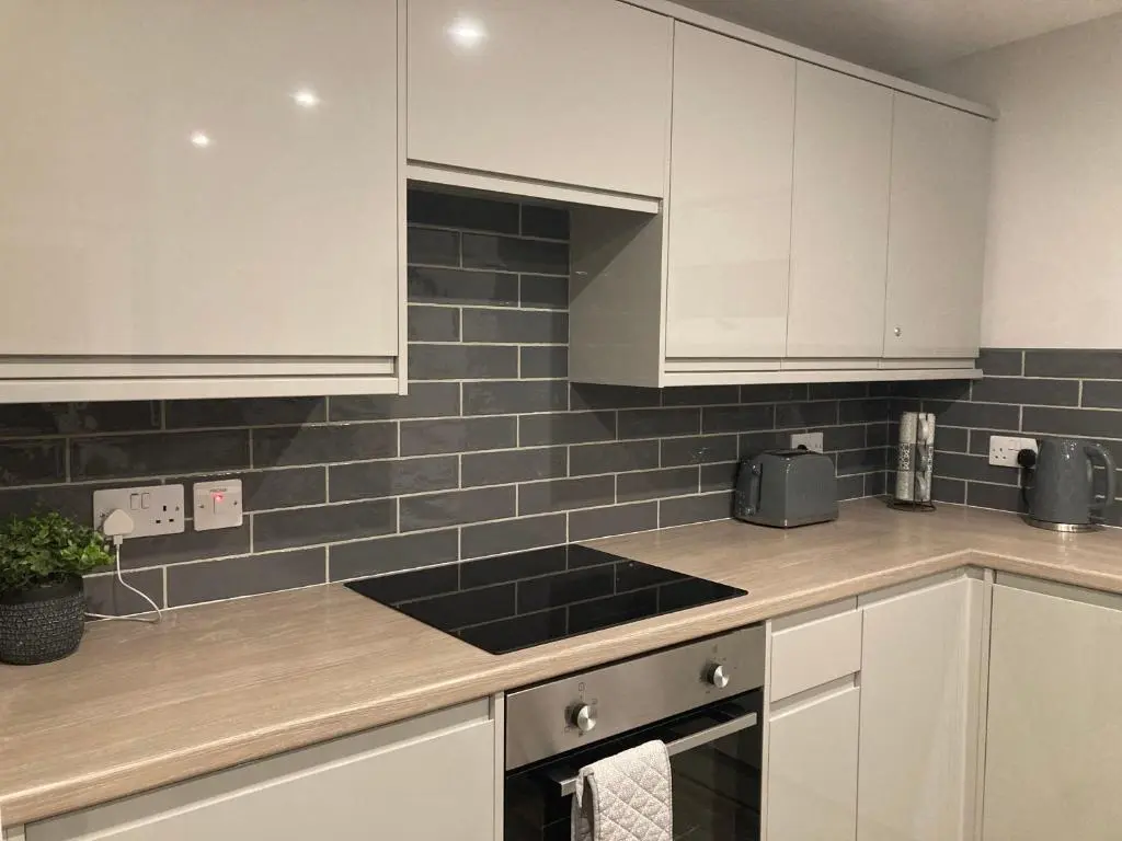 a kitchen with white cabinets and black tiles on the wall at North Coast Escapes in Thrumster