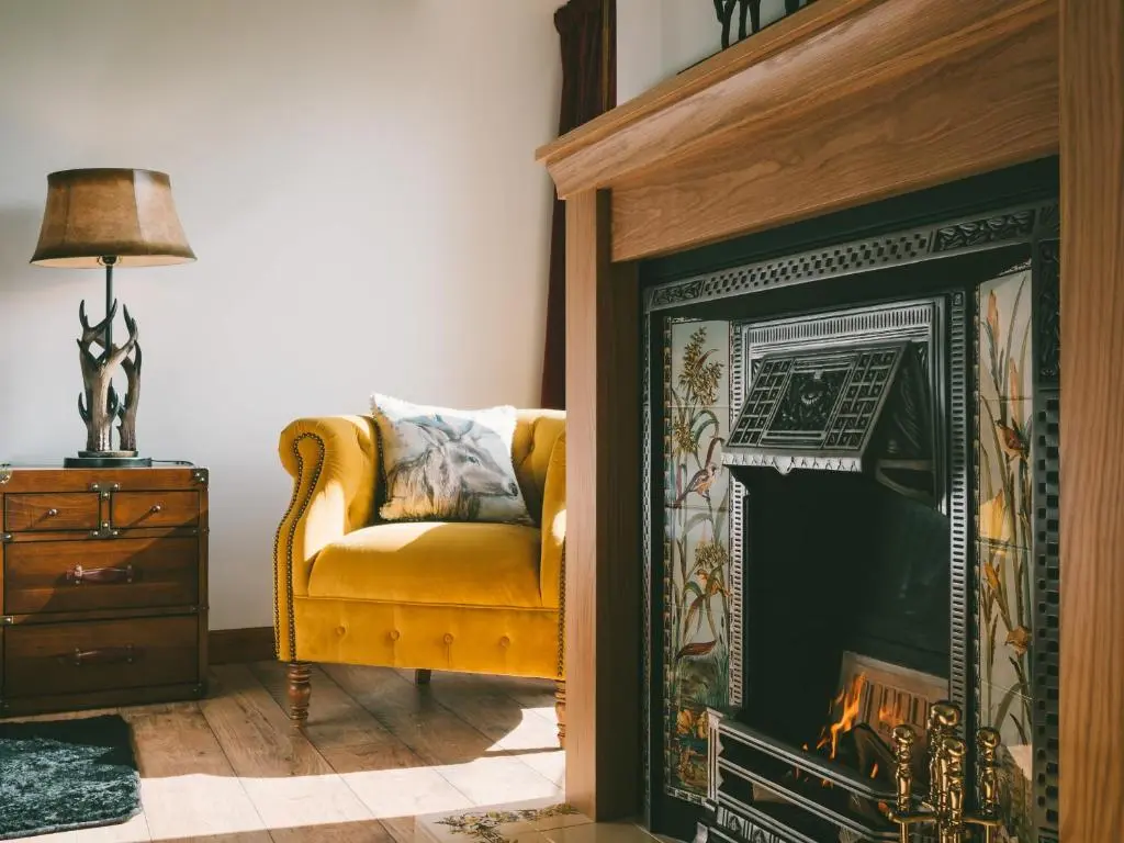 a living room with a yellow chair and a fireplace at The Eagle's Nest - large house with hot tub and sauna in Boat of Garten