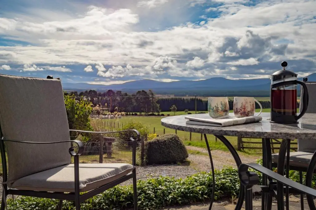 a table with a chair and a lamp on a patio at The Eagle's Nest - large house with hot tub and sauna in Boat of Garten