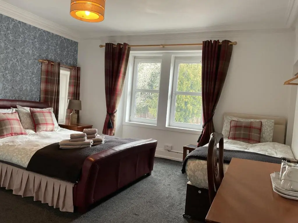 a bedroom with a bed and a table and a window at Richmond House Hotel in Fort Augustus