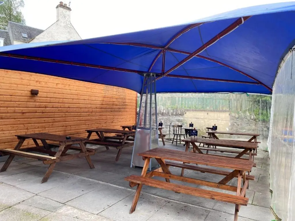 a group of picnic tables under a blue umbrella at Richmond House Hotel in Fort Augustus