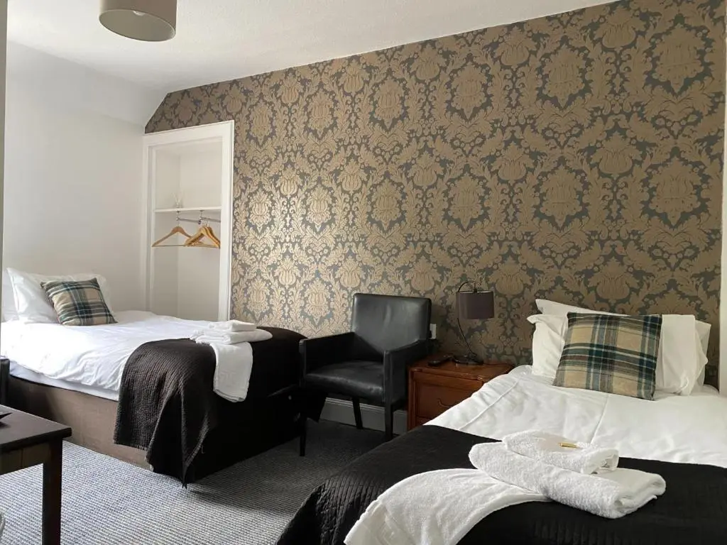 a hotel room with two beds and a chair at Richmond House Hotel in Fort Augustus