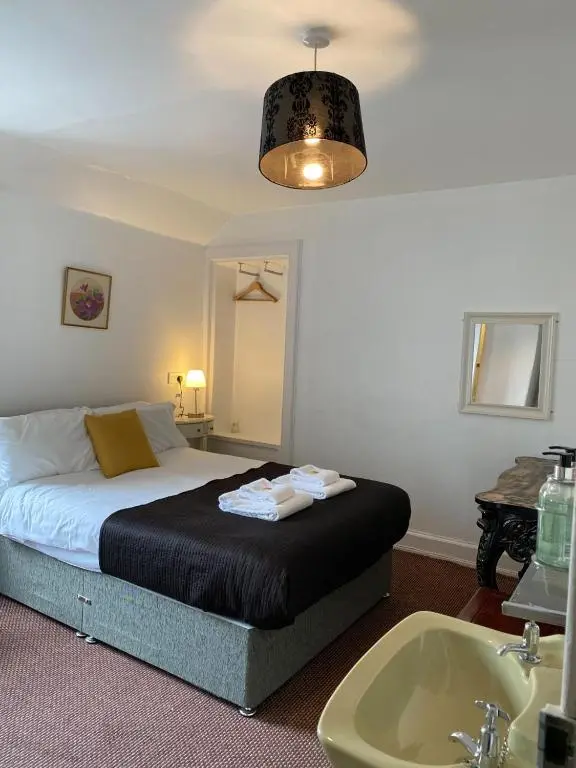 a bedroom with a bed and a sink and a tub at Richmond House Hotel in Fort Augustus