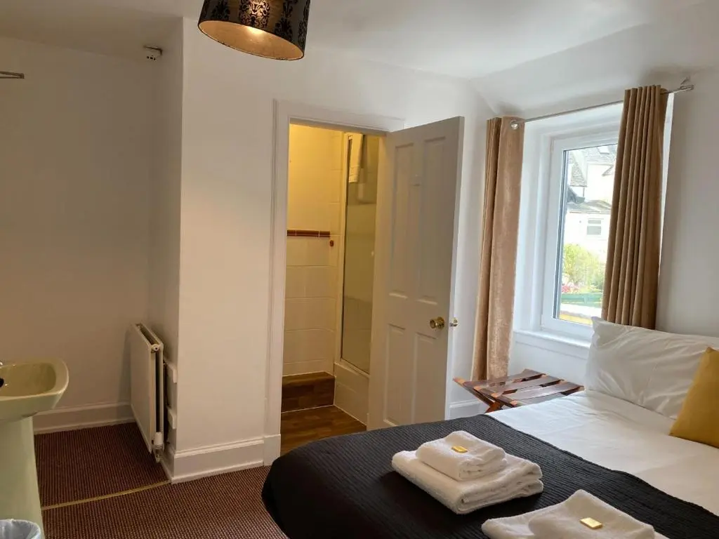 a bedroom with a bed with two towels on it at Richmond House Hotel in Fort Augustus