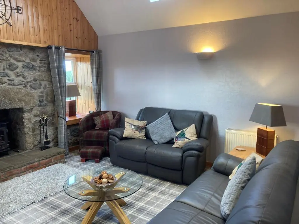 a living room with a couch and a fireplace at Meikle Aucheoch Holiday Cottage, plus Hot Tub, Near Maud, in the heart of Aberdeenshire in Peterhead