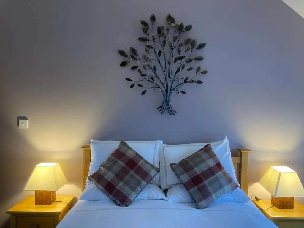 a bedroom with a bed with pillows and two lamps at Meikle Aucheoch Holiday Cottage, plus Hot Tub, Near Maud, in the heart of Aberdeenshire in Peterhead
