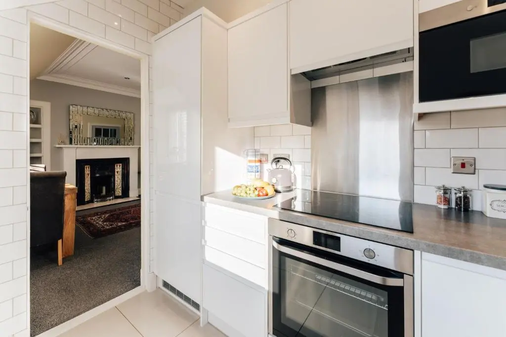 a kitchen with white cabinets and a stove top oven at Luxury Inverness central apartment private parking in Inverness