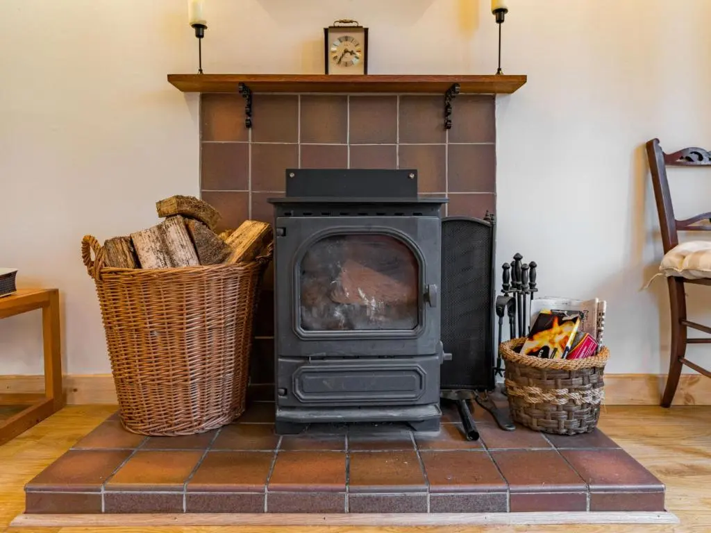 a wood stove in a living room with two baskets at Holiday Home Fishermans by Interhome in Inverness
