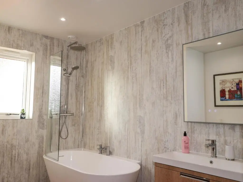 a bathroom with a tub and a sink and a shower at 3 Croftside in Aviemore