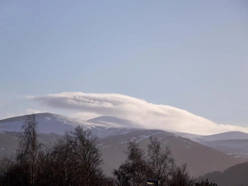 a cloud over the mountains with trees in the foreground at 3 Croftside in Aviemore