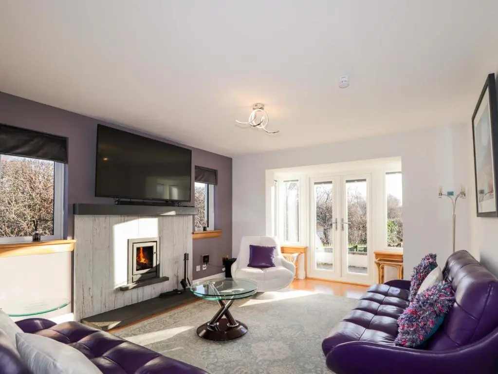 a living room with a couch and a fireplace at 3 Croftside in Aviemore