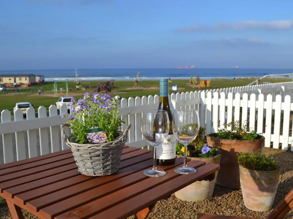 a wooden table with two glasses of wine and flowers at Tammie Norrie Cottage in Banff