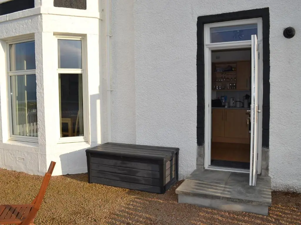 a door to a house with a chair next to it at Tammie Norrie Cottage in Banff