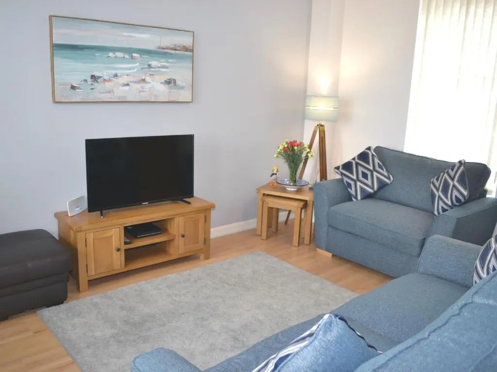 a living room with a couch and a flat screen tv at Tammie Norrie Cottage in Banff
