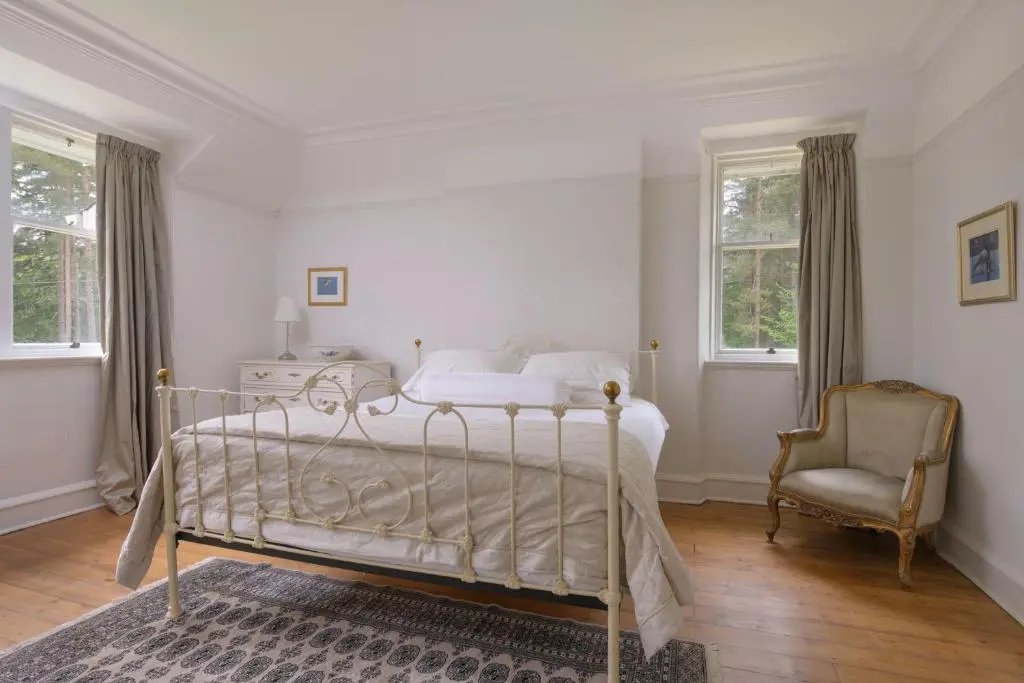 a bedroom with a bed and a chair and windows at Haven Retreat Scotland - Large 4 Bed House with Woodland garden, Aboyne ,Royal Deeside in Aboyne
