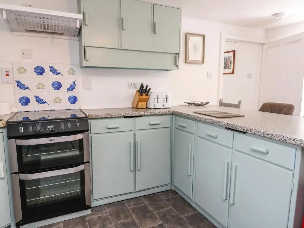 a kitchen with blue cabinets and a stove at Storkery Cottage in Aberdeen