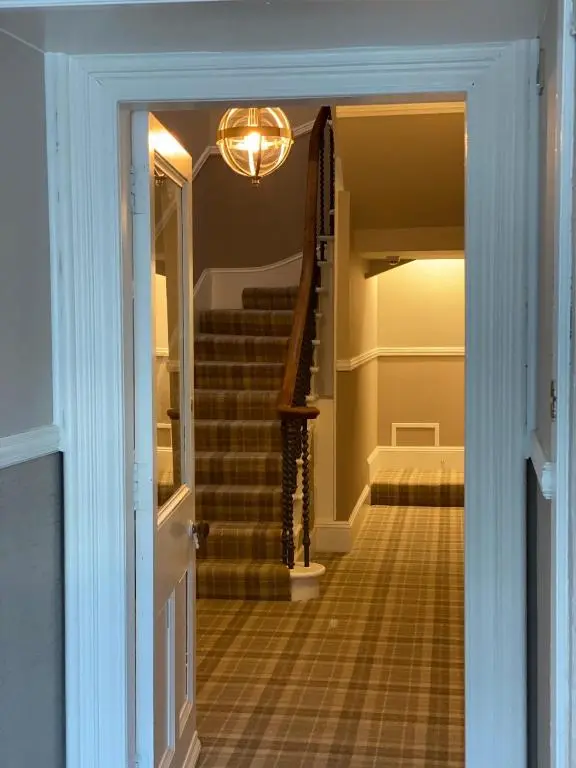 a hallway with stairs with a light and a door at Adrian's Guest House in Inverness