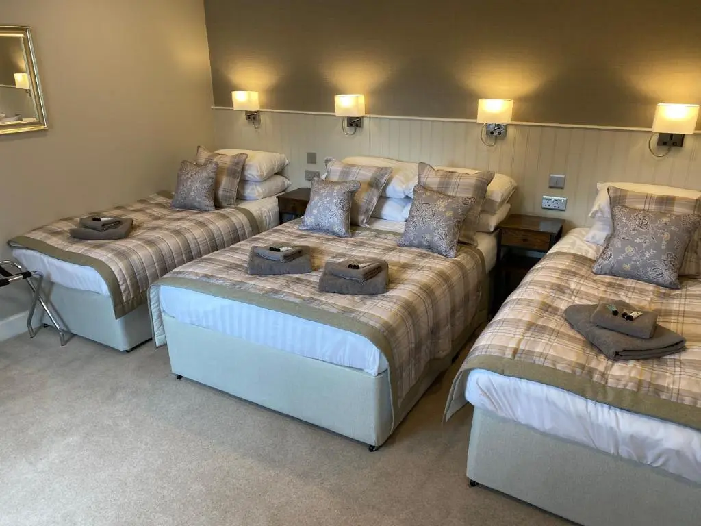 a room with three beds with pillows on them at Adrian's Guest House in Inverness