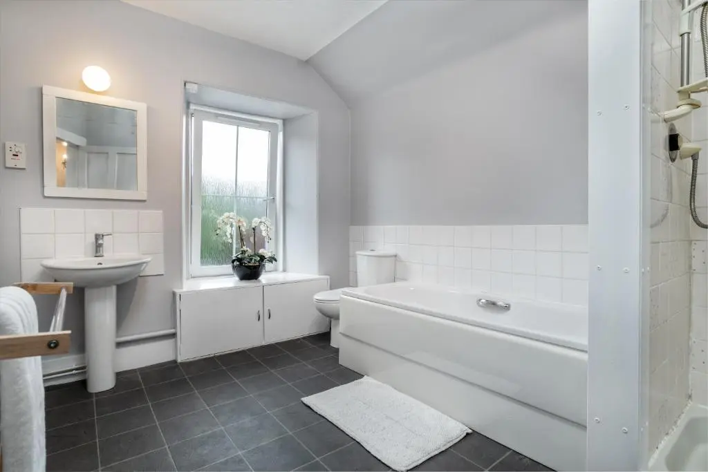 a white bathroom with a sink and a tub and a toilet at The Green Inn Rooms in Ballater