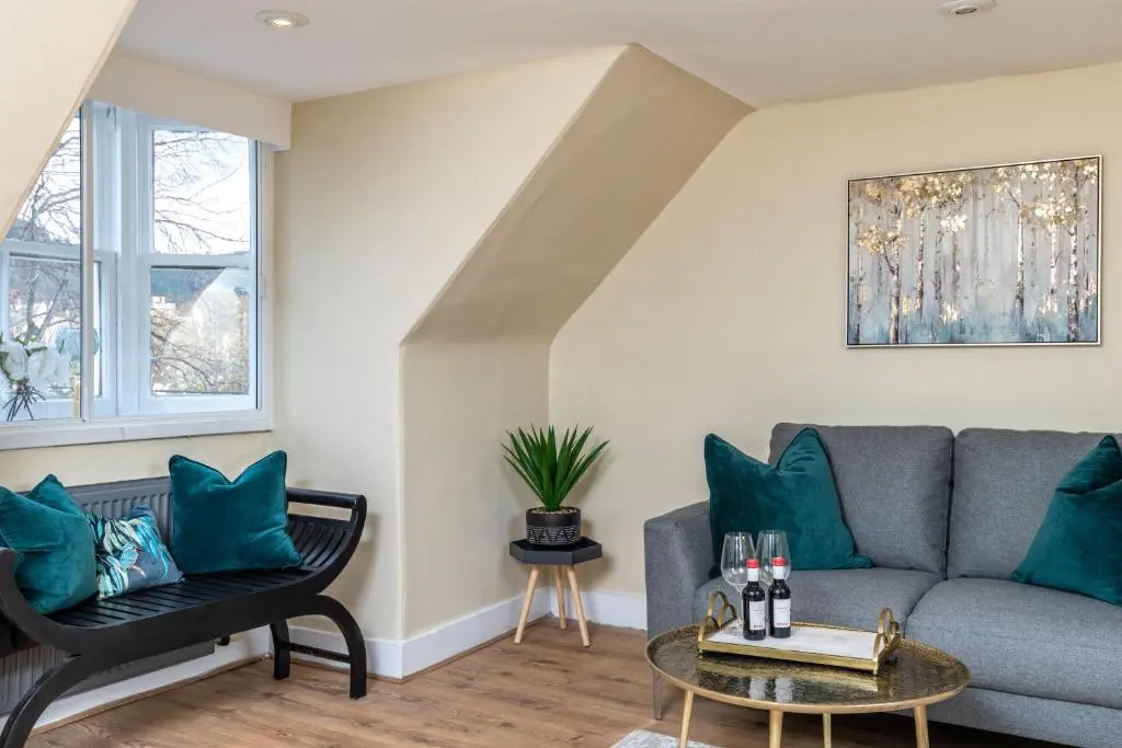 a living room with a gray couch and blue pillows at The Green Inn Rooms in Ballater