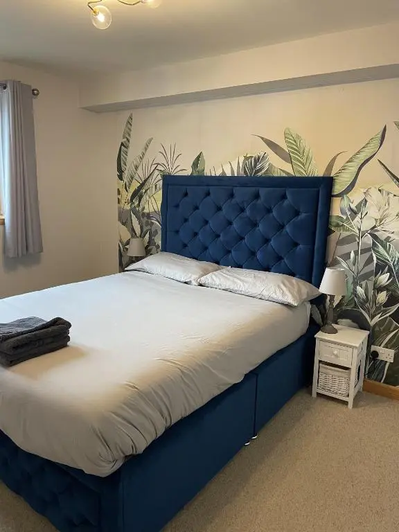 a blue bed with a blue headboard in a bedroom at Waterside View Apartment in Inverness