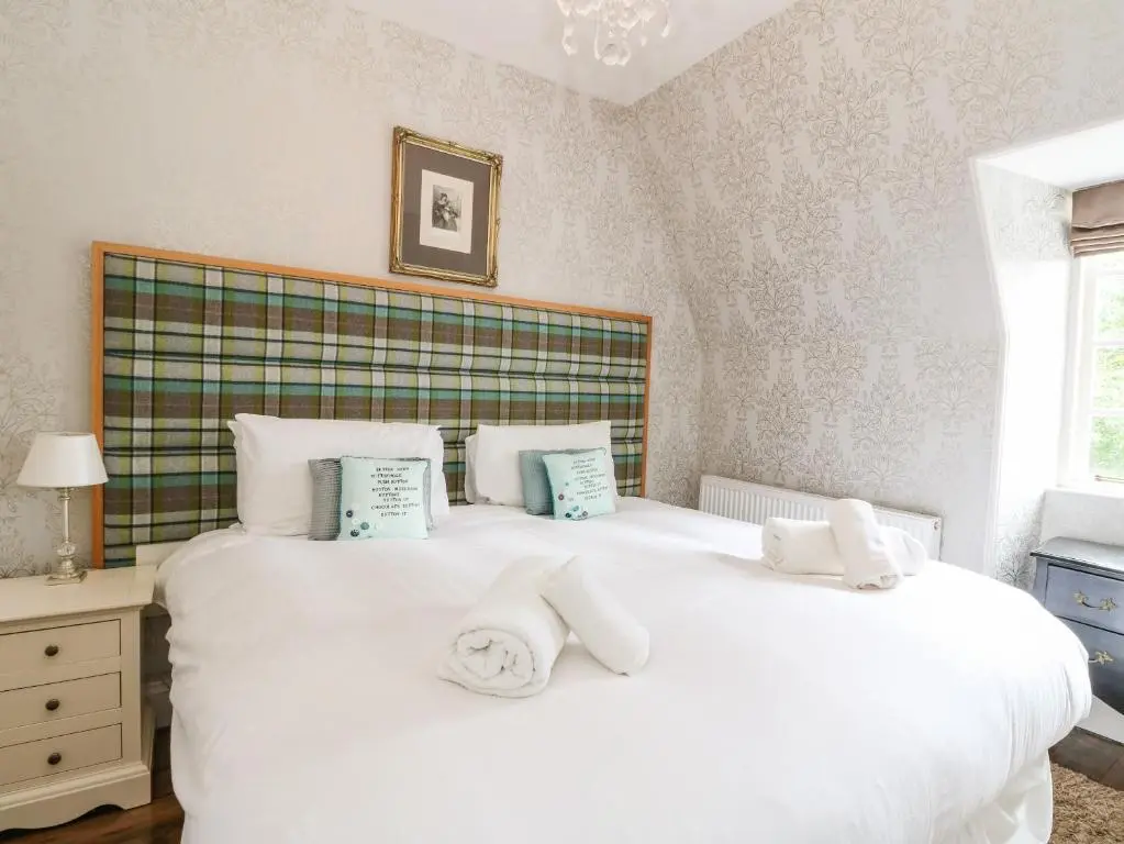 a bedroom with a large white bed with two pillows at Bearnock Lodge in Inverness