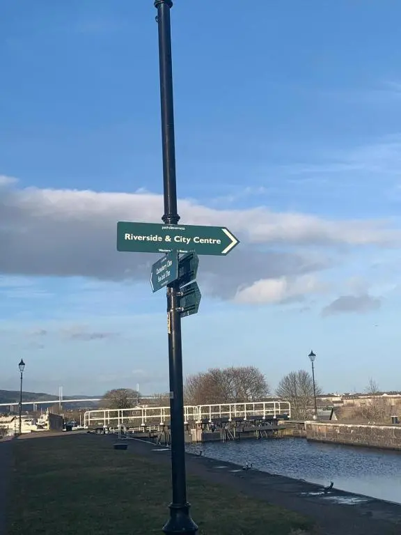 a pole with a street sign with a city center at Glencoe House Inverness in Inverness