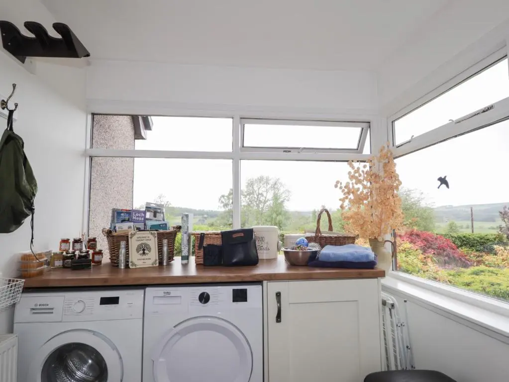 a kitchen with a washing machine and a window at Culreach Lodge in Grantown on Spey