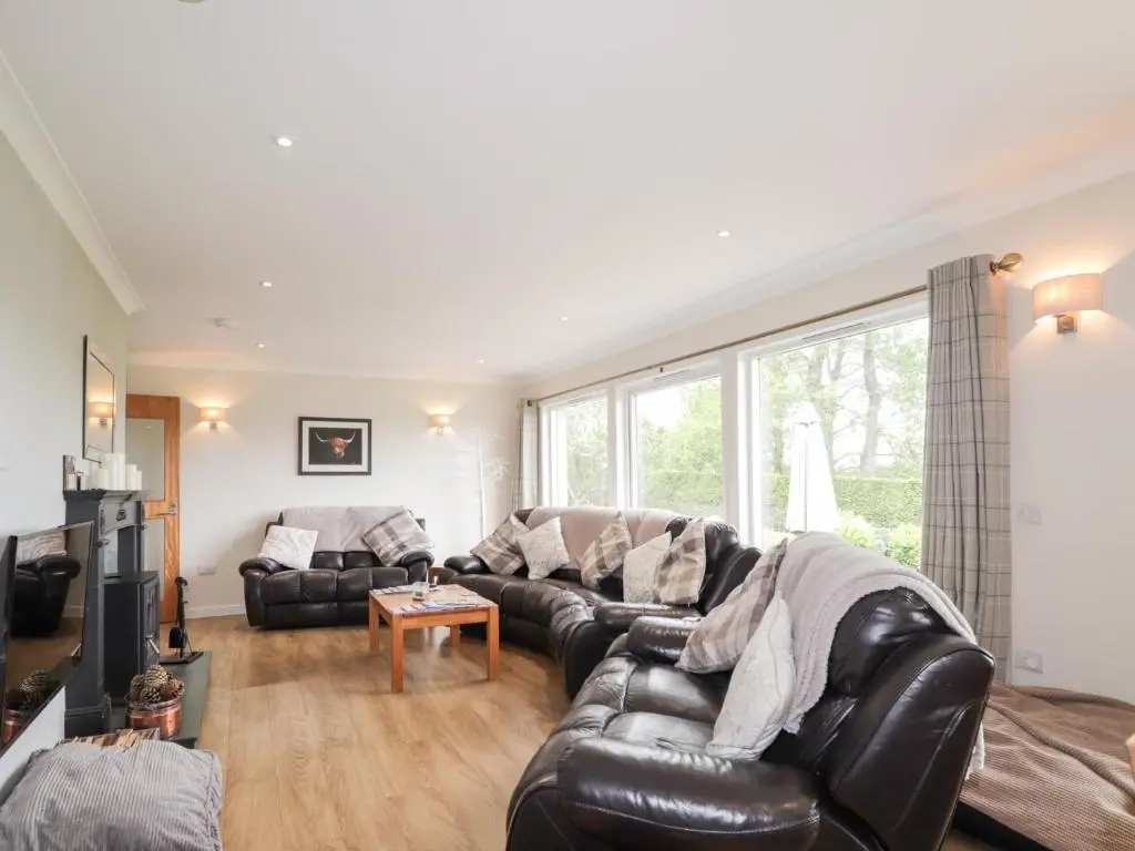a living room with a leather couch and a table at Culreach Lodge in Grantown on Spey