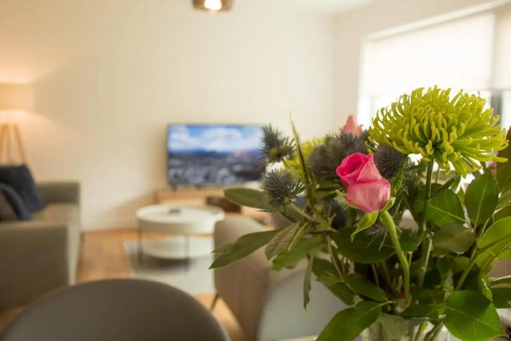a vase with a rose and flowers in a living room at 31 Caledonia Place in Aviemore
