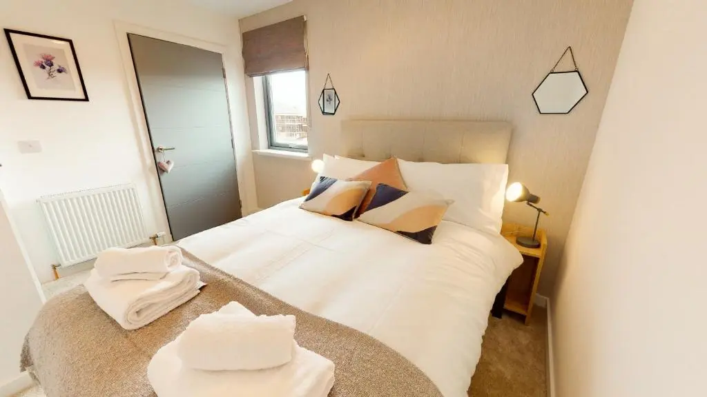 a bedroom with a bed with white sheets and pillows at 31 Caledonia Place in Aviemore