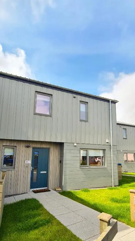 a large building with a blue door and grass at 31 Caledonia Place in Aviemore
