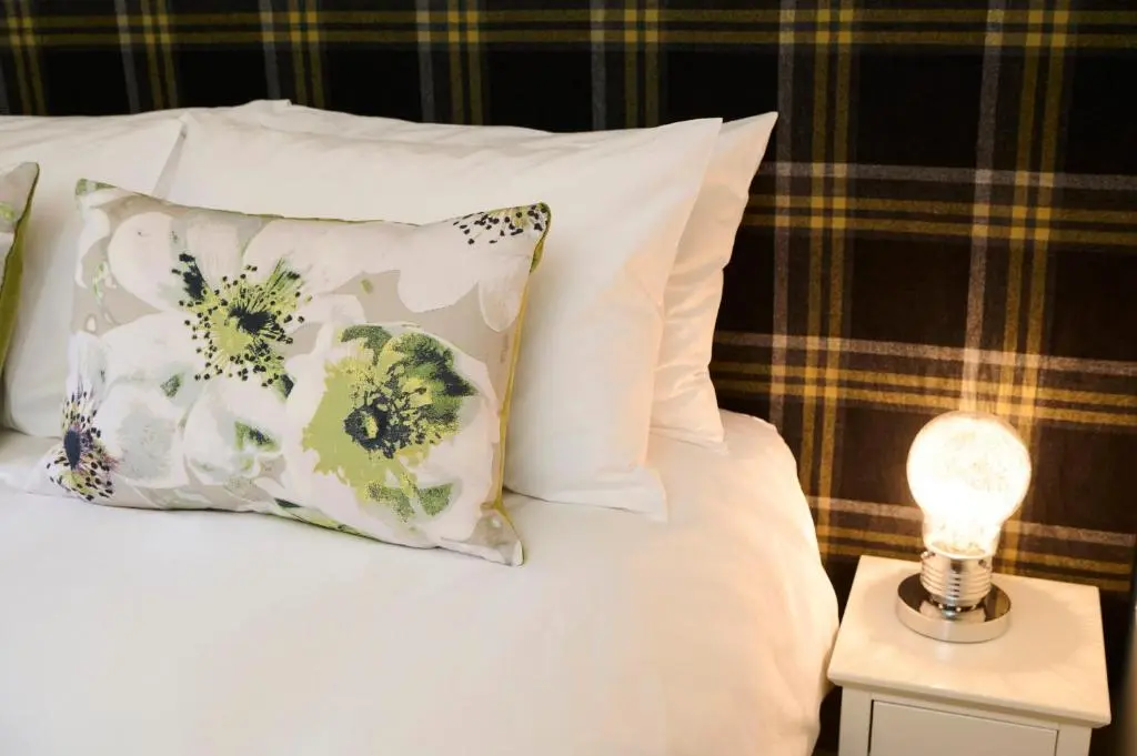 a bed with pillows and a lamp on a side table at Monkland Cottage in Nairn