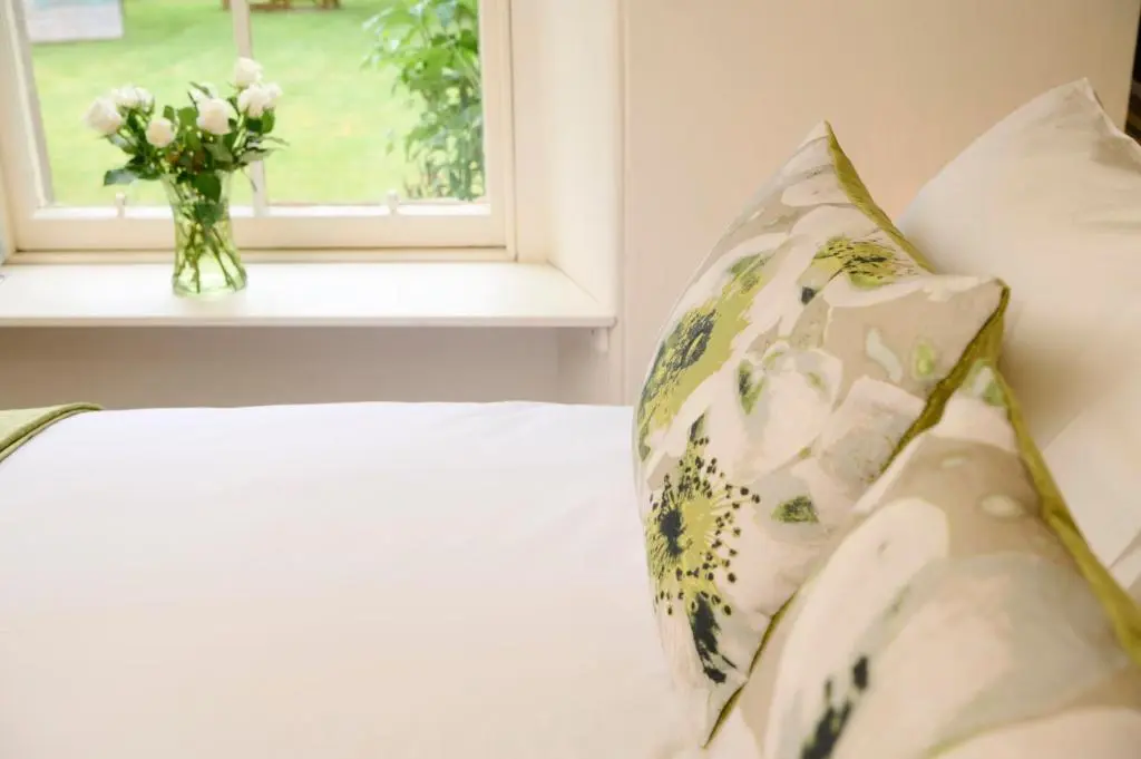a bed with a vase of flowers sitting next to a window at Monkland Cottage in Nairn