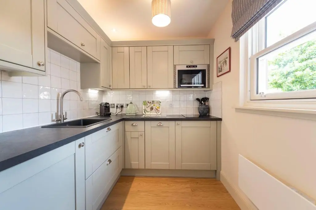 a kitchen with white cabinets and a sink and a window at Art House Apartments in Inverness