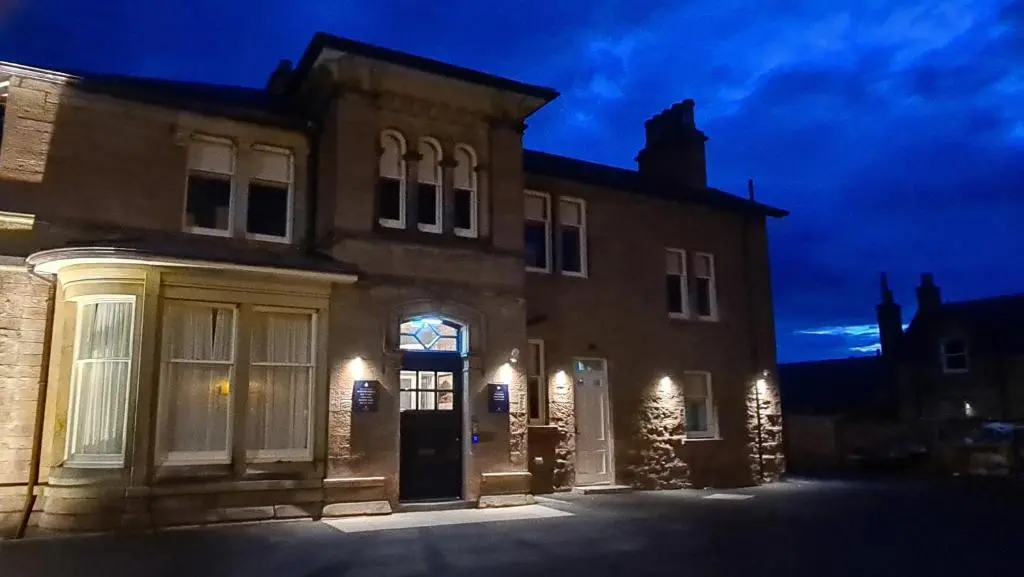 a large brick house with its door lit up at night at Art House Apartments in Inverness