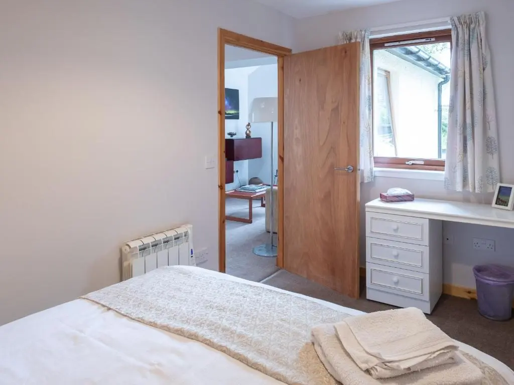 a bedroom with a bed and a desk and a window at Contemporary One Bedroom Apartment Close To All Amenities In Conservation Area in Tain