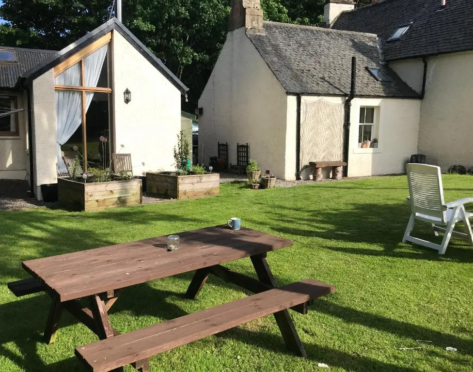 a wooden picnic table in the yard of a house at Contemporary One Bedroom Apartment Close To All Amenities In Conservation Area in Tain