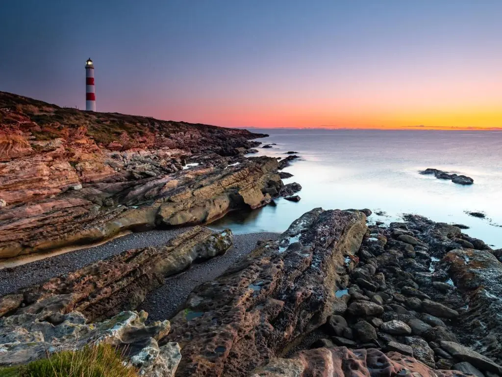 a lighthouse on a rocky shore with the ocean at Contemporary One Bedroom Apartment Close To All Amenities In Conservation Area in Tain
