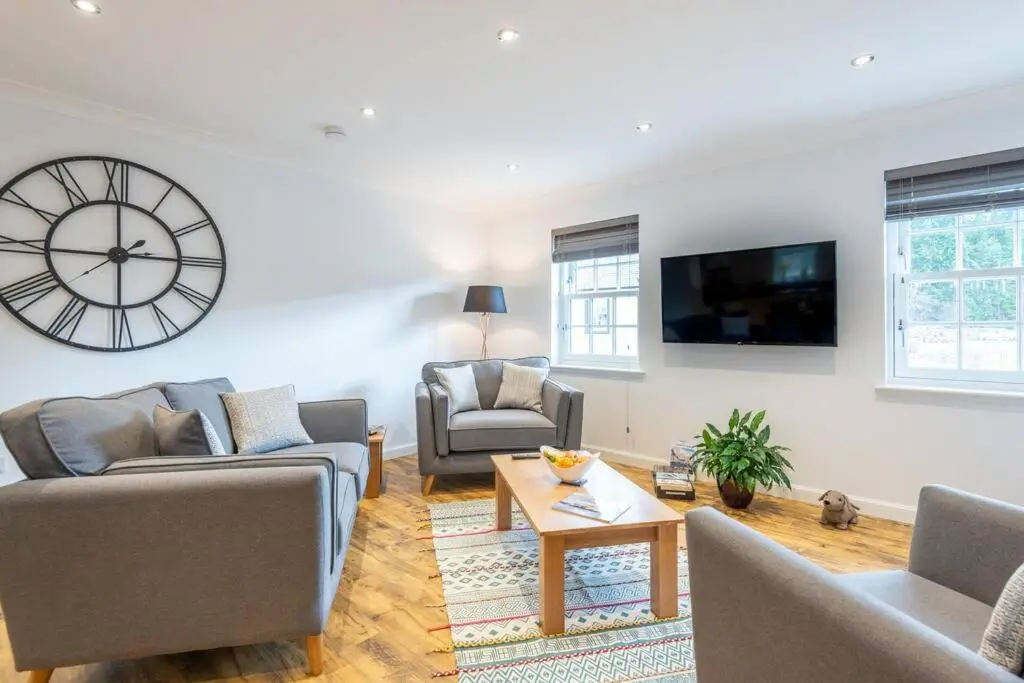 a living room with a large clock on the wall at Stylish & Modern Apartment in Inverness